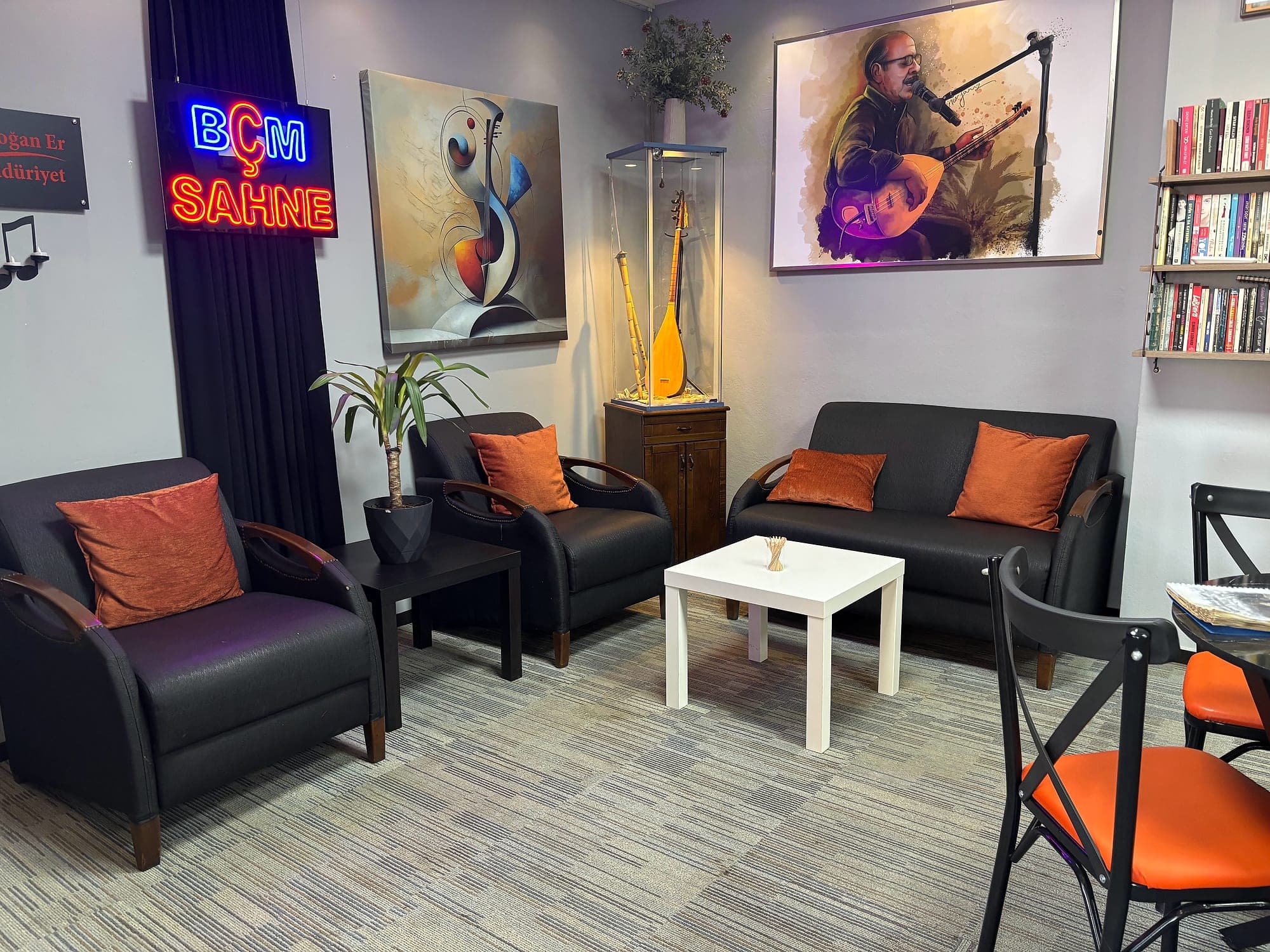 Öğrenci dinlenme salonu — 'Beş Sahne' neon tabelası ve sanatçı portreleri